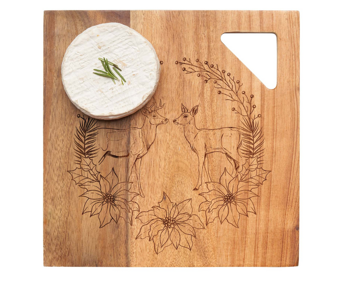 A round cheese wheel with rosemary sits on the Maple 12" x 12" Acacia Modern Geo Square | Deer Wreath board, engraved with deer and foliage. A triangular cut-out in the top right corner offers easy handling and elegant style.
