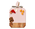The Maple 16" x 10" Acacia Heirloom Board n Blush features a ribbon-tied gold spreader and displays a red chili, three yellow cheese cubes, and a slice of fruit and nut bread—all beautifully arranged.