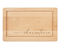 The Maple 16" x 10" Maple Wood Cutting + Cheeseboard features a grooved border and elegant "Charcuterie" script in cursive, making it ideal as a stylish charcuterie or cheese board.