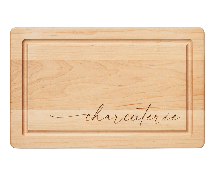The Maple 16" x 10" Maple Wood Cutting + Cheeseboard features a grooved border and elegant "Charcuterie" script in cursive, making it ideal as a stylish charcuterie or cheese board.