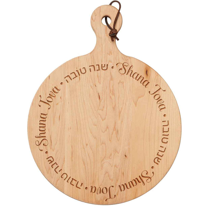 The Maple 16x12" Artisan Round Board—Shana Tova Round features a handle, leather loop, and festive engraving, making it a perfect board to celebrate Rosh Hashanah and the new year.