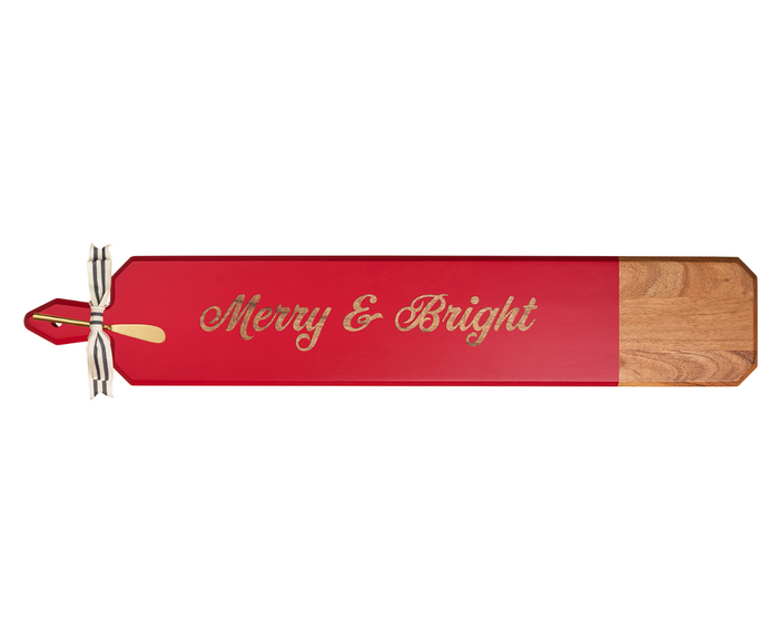 The Maple 34" x 6" Acacia Heirloom Board features a red section with “Merry & Bright” in gold script, a gold-tipped handle tied with a ribbon, and comes with a gold spreader.