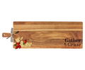 The Maple 35" x 12" Acacia Wood Thick Handle Board features "Gather & Graze" engraving and comes with a gold spreader—ideal for serving cheese, crackers, and fruit while making a charming statement in your kitchen.