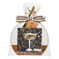 The Maple 9.75" x 8" Board Gift Kit: Gold Disco includes an acacia wood charcuterie board, gold straw, black napkins with “Pop, Clink, Fizz, Durr!” in gold and white print, all wrapped in clear plastic with a black and white ribbon.