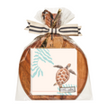 The Sophistiplate 9.75" x 8" Board Gift Kit: Pastel Sea features a round acacia wood charcuterie board with a notepad showing a sea turtle, wrapped in clear cellophane with a striped ribbon and gold-toned accents.