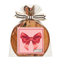 Sophistiplate’s 9.75" x 8" Board Gift Kit: Pink Bows features a wooden serving board and napkins with pink bow designs, wrapped together in clear plastic and finished with a striped ribbon and bow on top.