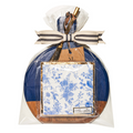 The Maple 9.75" x 8" Board Gift Kit: Timeless is wrapped in clear plastic and features a blue and brown round acacia wood board, white napkins with blue floral designs, a striped bow with a gold pen and tag attached on top.