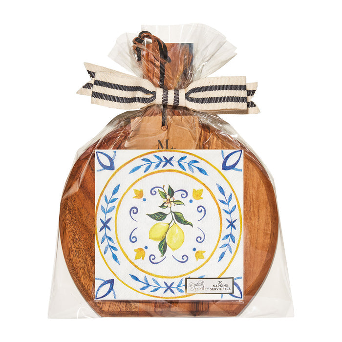 The Sophistiplate Capri Coast 9.75" x 8" Board Gift Kit, wrapped in clear plastic with a black and white striped bow, includes a cocktail napkin with painted lemon, green leaves, yellow flowers, and blue accents.