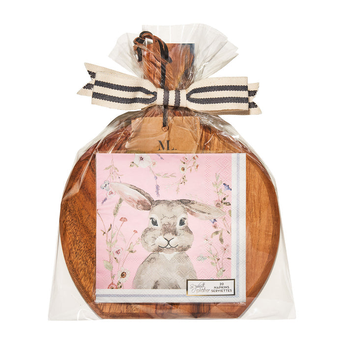 The Sophistiplate 9.75" x 8" Charming Easter Board Gift Kit features a round acacia wood board wrapped in plastic with a black and white ribbon, plus cocktail napkins with a watercolor bunny on pink florals—perfect for gifting.