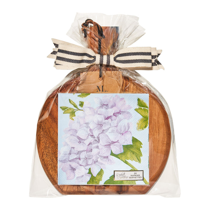 The Sophistiplate 9.75" x 8" Board Gift Kit features a round acacia wood board wrapped in clear plastic with a striped ribbon and cocktail napkins adorned with hydrangeas, perfect for an elegant charcuterie setup. Spreader not included.
