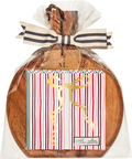 A 9.75″ x 8″ Sophistiplate Board Gift Kit—Tis the Season—is wrapped in clear plastic with a striped bow and features acacia wood, holding red and white striped cocktail napkins with a gold ribbon design.