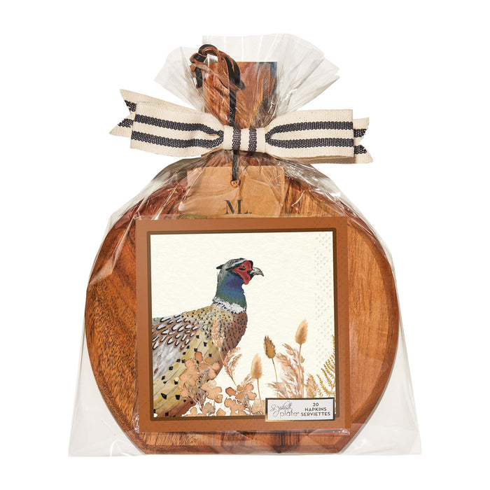 The Sophistiplate 9.75" x 8" Woodland Harvest Board Gift Kit features a round acacia wood board with handle, wrapped in clear plastic and finished with a striped ribbon and card—ideal as a charcuterie or appetizer serving tray.