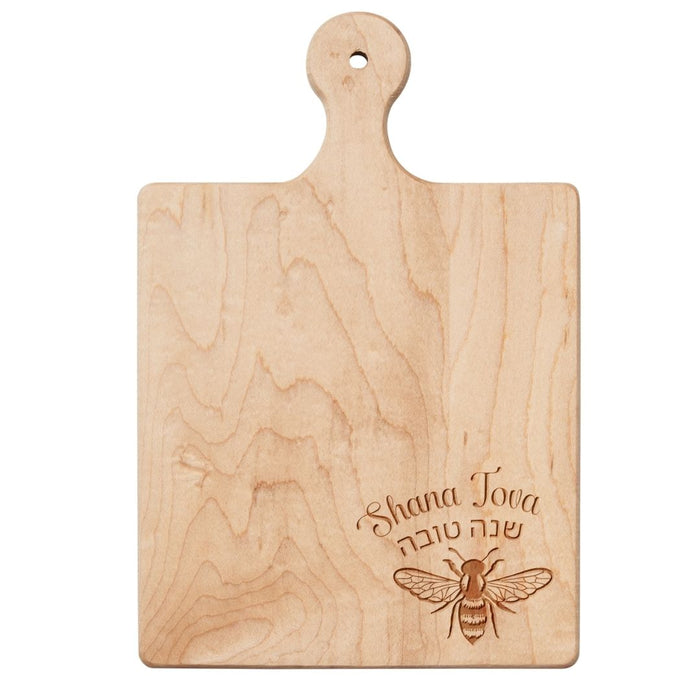 The Maple 9"x6" Maple Wood Board | Shana Tova is perfect as a cheese or charcuterie tray, featuring a handle and an engraved bee with “Shana Tova” in English and Hebrew in the bottom right corner.