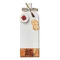 The Maple Acacia Bevel Board Long White (20x7") features "Joy To The World," a gold spreader, ribbon at the handle, plus brie cheese with pomegranate seeds and crackers for a festive touch.
