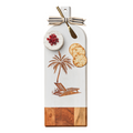 The Maple Acacia Bevel Board Long White w/ Gold Spreader & Ribbon | Palm Tree (20 x 7”) displays round cheese, pomegranate seeds, two crackers, and a gold cheese knife, with a ribbon tied to the handle.