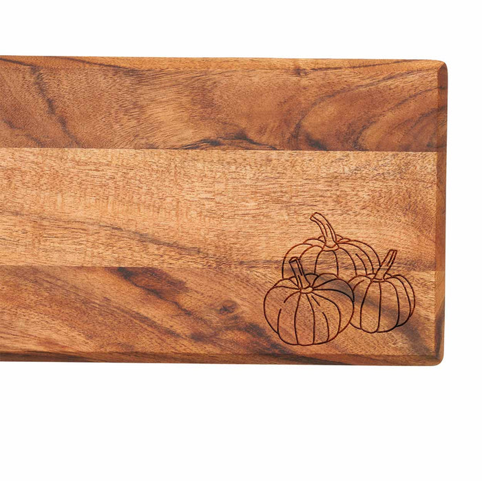 The Maple Acacia Bevel Board w/ Ribbon & Gold Spreader Knife features an engraved trio of pumpkins in the corner. Size: 20 x 7".