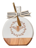 The Maple Acacia Bevel Board White w/ Gold Spreader Knife | Honeybee (9.75 x 8") features a gold bee and floral design, topped with a striped ribbon—perfect for serving charcuterie and cheese in style.