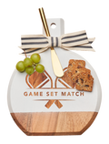 The Maple Acacia Bevel Board White (9.75 x 8") features “GAME SET MATCH” above crossed racquets, striped ribbon accent, and a gold spreader knife—perfect for serving cheese, crackers, and grapes in style.