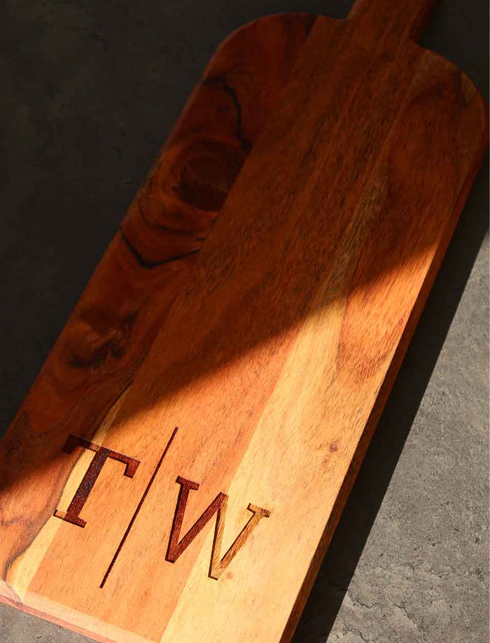 The Maple Acacia Bevel Board with Long Handle (20 x 7") features personalized engraving, making it a standout gift. Its elegant design and custom touch add style to any setting, ideal for gifting or entertaining.