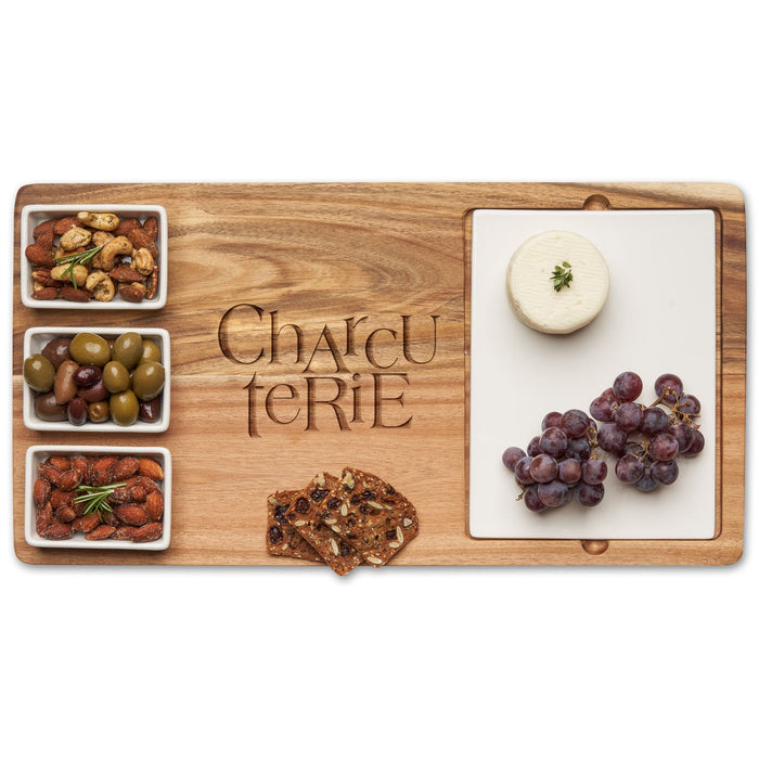 The Maple Acacia Fête Set Tray | Charcuterie Stacked (18" x 9.5") features an acacia wood board engraved “Charcuterie" and ceramic dishes for cheese, grapes, nut mix, olives, almonds, and crackers—perfect for stylish entertaining.
