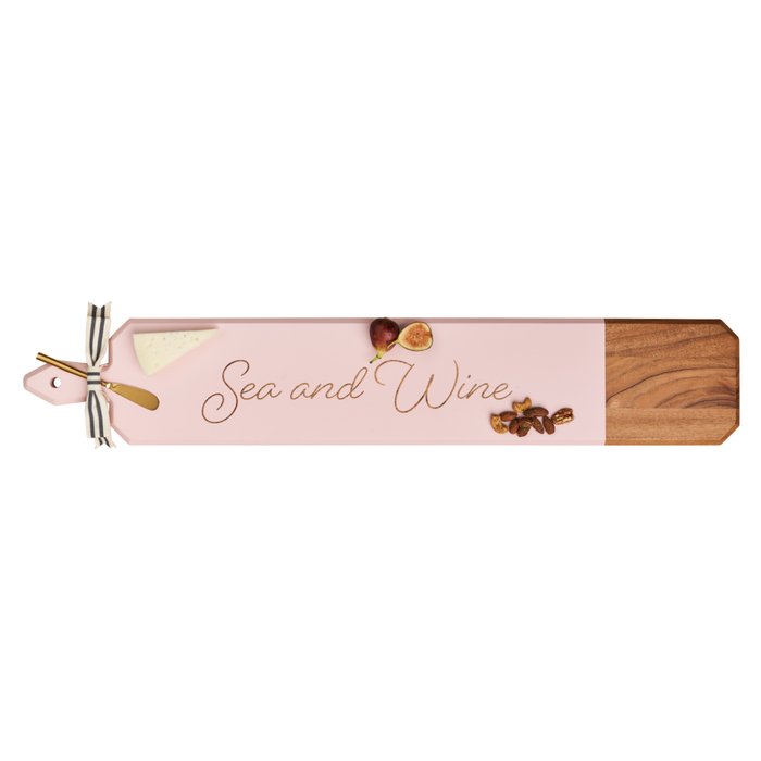 The Maple Acacia Heirloom Board Skinny in pink (34 x 6") features "Sea and Wine" script, with cheese, figs, and nuts on top. Includes a gold spreader tied with ribbon.