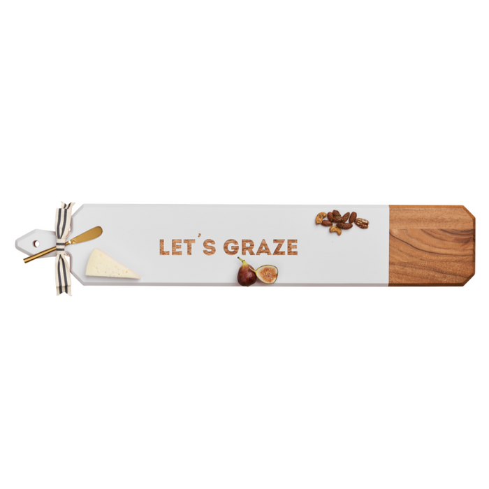 The Maple Acacia Heirloom Board Skinny in white, 34 x 6", features gold "Let's Graze" lettering and comes with a gold spreader and ribbon—perfect for serving cheese, figs, and nuts.