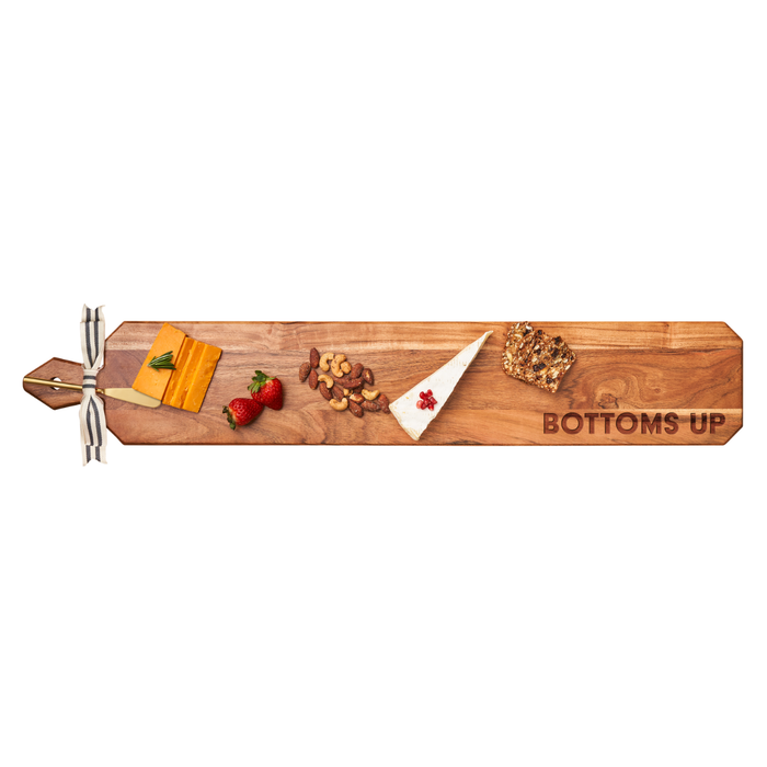 The Maple Acacia Heirloom Board Skinny (34 x 6") includes a gold spreader and ribbon, engraved with "BOTTOMS UP" on the right side, and is beautifully styled with cheese, berries, nuts, and seeded bread.