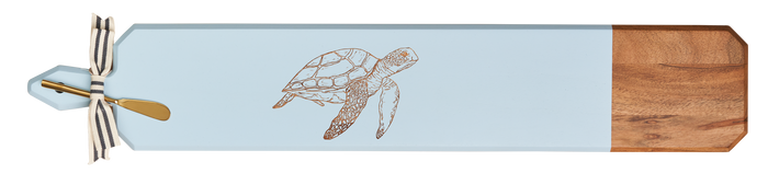 The Maple Acacia Heirloom Board w/ Handle Skinny (34x6") in light blue features an engraved turtle, a wooden acacia end section, and comes with a striped ribbon and small gold-colored spreader.