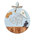 The Maple Acacia Heirloom Board with Handle (20 x 16") features a round design, gold spreader tied with a gray & white ribbon, and engraved Mr. Mrs. heart detail—perfect for serving cheese, crackers, grapes, and more.