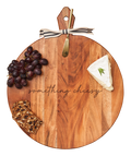 The Maple Acacia Heirloom Board with Handle (20 x 16 x .6") features "something cheesy" engraving, comes with a gold spreader tied with a gray & white ribbon, and is styled with cheese wedge, red grapes, and seeded crispbread.