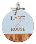 The Maple Acacia Heirloom Board with Handle features a round light blue top, "Lake House" and crossed oars engraving, a gray & white ribbon, and a gold spreader—perfect for serving bites at any gathering. Size: 20 x 16".