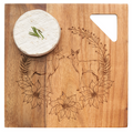 A round wheel of cheese topped with chives sits on the Maple Acacia Modern Geo Square | Deer Wreath 9 x 9" board, engraved with two deer, flowers, and foliage, featuring a triangular cut-out in the corner.