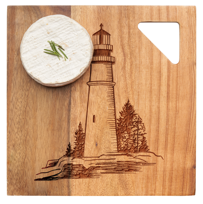 A wheel of cheese with chives rests on the Maple Acacia Modern Geo Square board (9 x 9"), engraved with a lighthouse and trees.