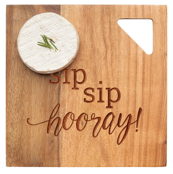 A wheel of cheese with herbs rests on Maple’s Acacia Modern Geo Square Sip Sip Hooray 9 x 9" board—engraved in mixed fonts—perfect for charcuterie.