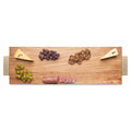 A Maple Acacia Serving Board with Gold Handles (30 x 10") displays two cheese wedges, green and purple grapes, sliced salami, and crackers, all neatly arranged against a white background.