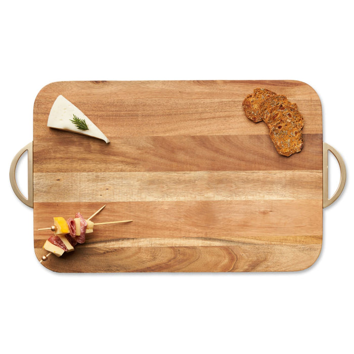 The Maple Acacia Wood Cutting + Cheeseboard w/ Gold Handles (18 x 12”) displays a wedge of herbed cheese, crispbread, and a meat, cheese, and veggie skewer—all artfully arranged on its elegant surface.