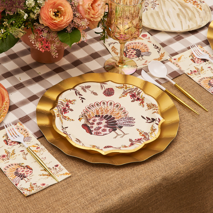 A festive table setting featuring Sophistiplate’s Amber Harvest Dinner Plates (8pk) atop a gold charger, paired with floral napkins, gold utensils, and a flower centerpiece on a plaid and burlap tablecloth.