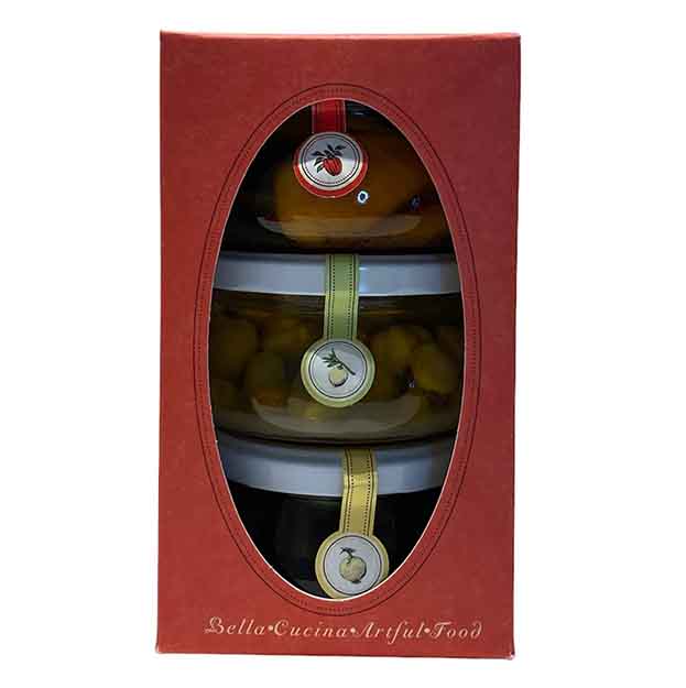 The Antipasti Gift Box by Bella Cucina features three stacked glass jars of antipasti with colorful ribbons in a red box with an oval window—ideal for pairing with cheese boards or charcuterie spreads.