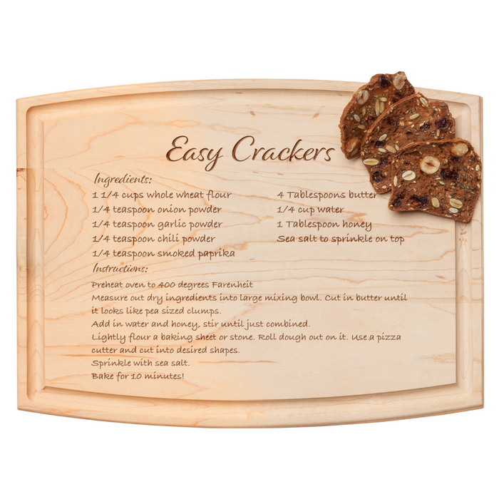 A handwritten Easy Crackers recipe appears on the Maple Arched Artisan Maple Board | Recipe Board | 12 x 9", with three dark, seeded crackers placed in the top right corner beside the listed ingredients and instructions.