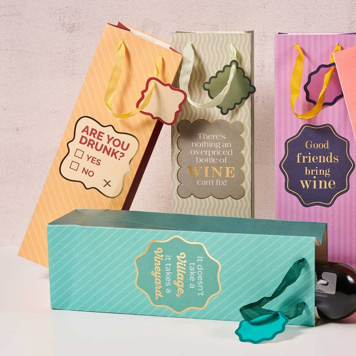 The "Are You Drunk- Wine Bag" by Drinks On Me features funny wine-themed text, decorative ribbon handles, and a tag. This reusable bag, shown with a bottle on a neutral surface, makes the perfect hostess gift.