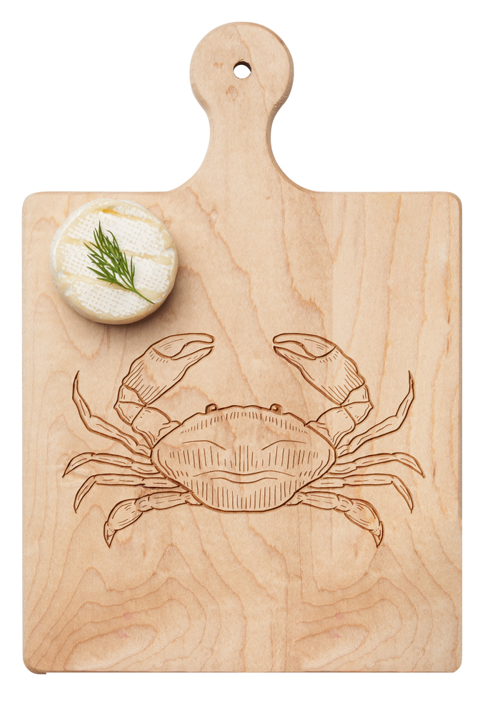 A round cheese wheel with dill rests on the Maple Artisan Maple Paddle Board | Crab | 9" x 6", featuring a crab engraving.