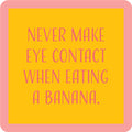 The Banana Coaster by Drinks On Me features a yellow square with a pink border and pink text: "Never make eye contact when eating a banana." A hilarious gift for housewarmings or quirky bar cart accessories.
