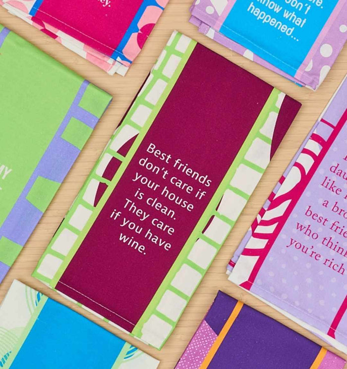 The Best Friends Dish Towel by Drinks On Me features a maroon and green design with the quote "Best friends don’t care if your house is clean. They care if you have wine." Perfect kitchen humor and great for housewarming gifts.