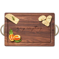 The Maple Black Walnut Wood Cutting + Cheeseboard (18 x 12") features "merry everything" engraved in the center and metal handles, perfect for displaying cheese, bread, fruit, and more. Made in the USA.