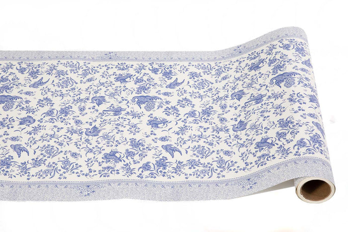 The Hester & Cook Blue Regal Peacock Runner (20x25") features a white background with detailed blue floral, peacock, and animal motifs bordered by elegant trim—ideal for creative gift wrap or as a distinctive paper table runner.