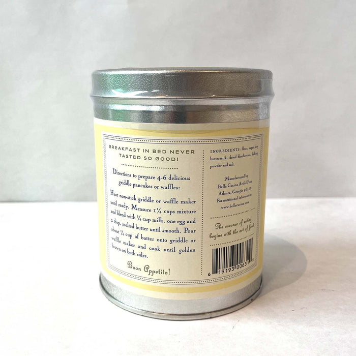 A silver tin of Bella Cucina Blueberry Buttermilk Pancake & Waffle Mix features a cream label with directions, ingredients, and “Breakfast in bed never tasted so good!” on a white background.