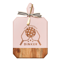 The Maple Acacia Heirloom Board in Blush features “The Greatest Dinnker” engraved above a paddle and ball, comes with a gold spreader tied with gray & white ribbon to the handle, and is perfect for serving charcuterie. Size: 16 x 10".