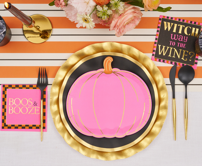A festive Halloween table features Sugarplum's Boo Bold Assorted Die Cut Salad Plates, gold and black chargers, black cutlery, a floral centerpiece, striped runner, and napkins with "BOOS & BOOZE" and "WITCH WAY TO THE WINE?"—all perfect party essentials.