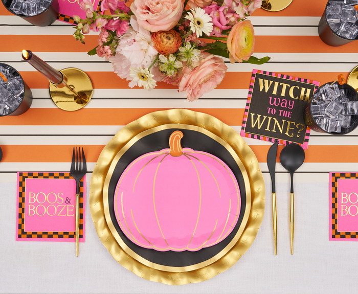 A Halloween table setting features Sugarplum’s Boo Bold Assorted Die Cut Salad Plates, set on gold and black chargers with coordinating black and gold cutlery, festive napkins, and a floral centerpiece.