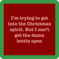 A red square coaster from Drinks On Me features beige text: “I’m trying to get into the Christmas spirit. But I can’t get the damn bottle open”—a funny Bottle Open Coaster for your bar cart or as a cheerful drink accessory.